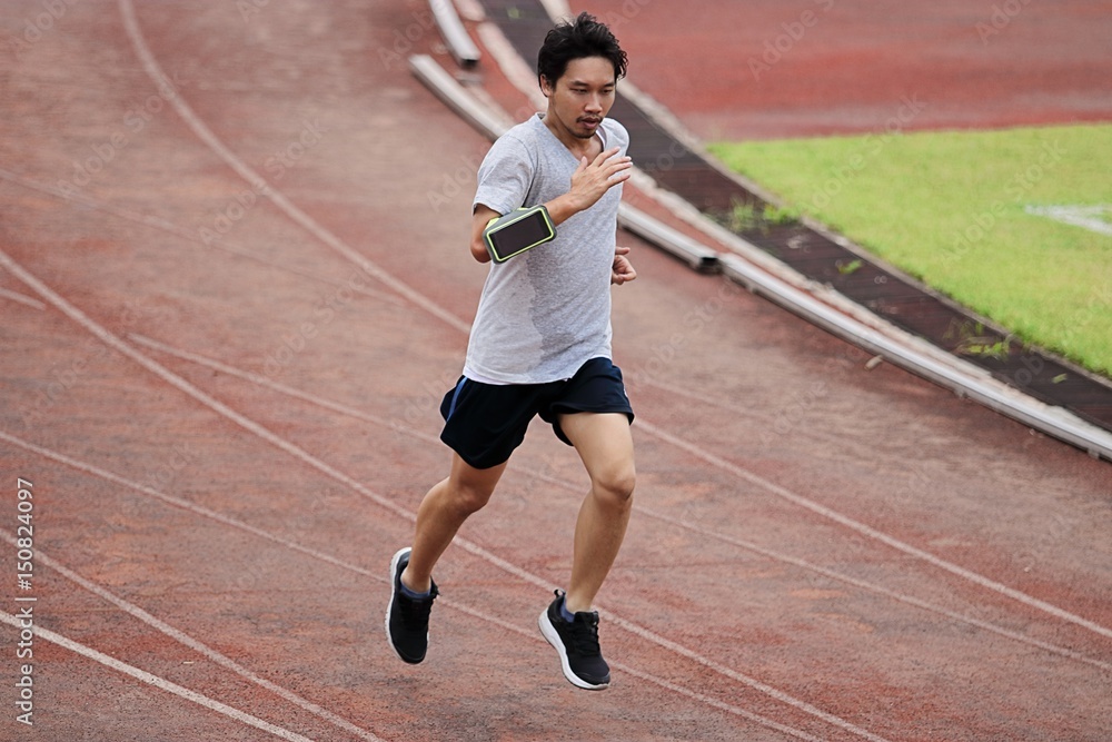Lifestyle of young healthy Asian man runner running on racetrack Lifestyle of young healthy Asian man runner running on racetrack