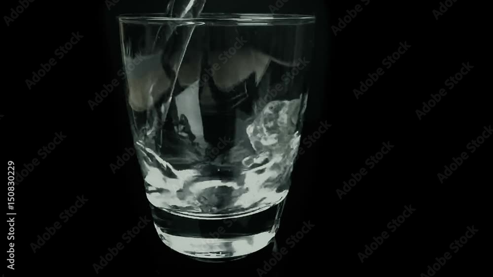 filling a glass with water, nutrition and health-care concept, slow motion, on black background filling a glass with water, nutrition and health-care concept, slow motion, on black background