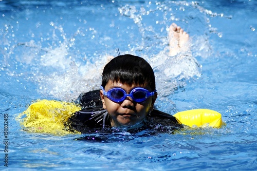 Young boy swimming in a swimming pool.