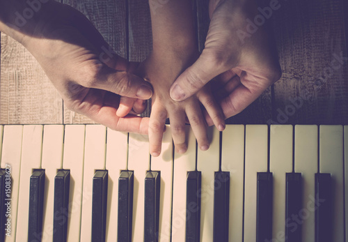 Wallpaper Mural Mother teaches the daughter to play the piano. Concept Mother's Day. Female and children's hands. Vintage toning. Top view Torontodigital.ca