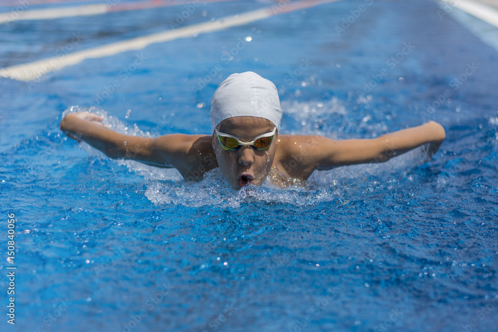 Close up action shot of child athlete swimming butterfly style