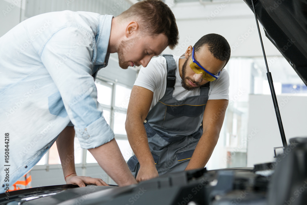 Professional mechanic and his customer at the garage Professional mechanic and his customer at the garage