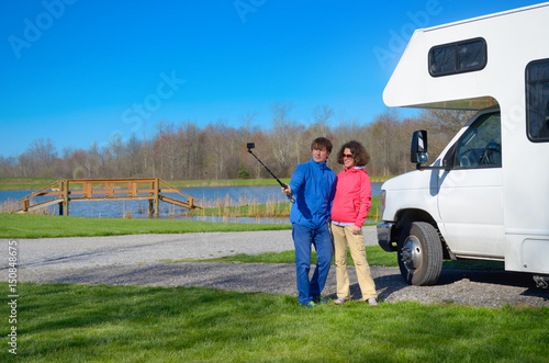 Family vacation, RV travel, happy couple making selfie in front of camper on holiday trip in motorhome
