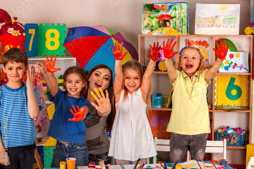 Small students with teacher finger painting in art school class. Teacher cheers children in kindergarten. Mom and kids at home. Craft drawing education develops creative abilities of children.