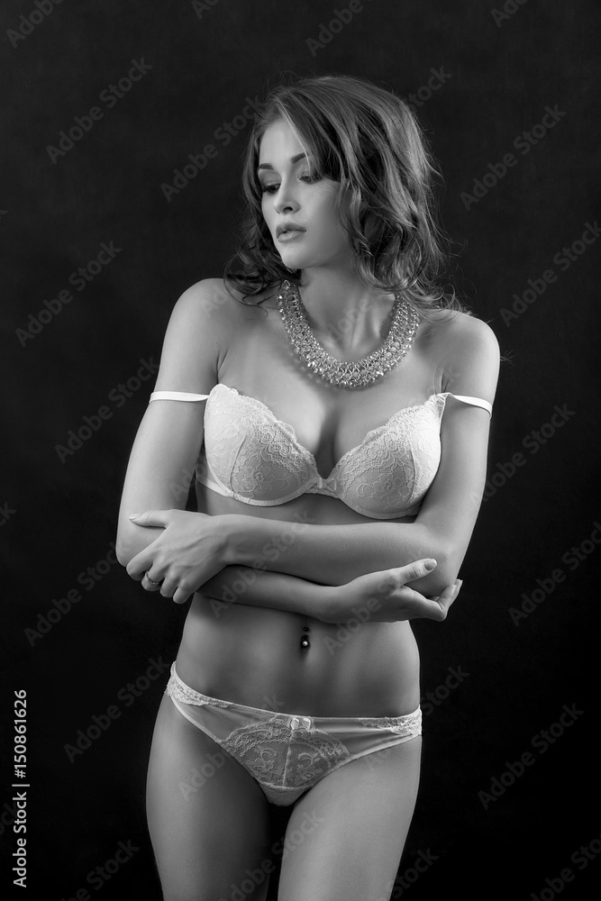 Fototapeta premium beautiful woman in lingerie show her slim body on black background, monochrome