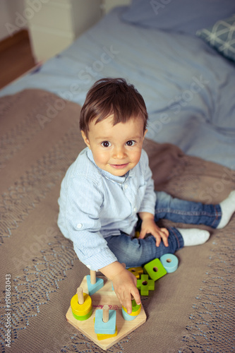 Little boy plays on the bed. A happy little kid.