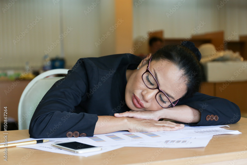 working woman who wears glasses sleep on the document on wood desk