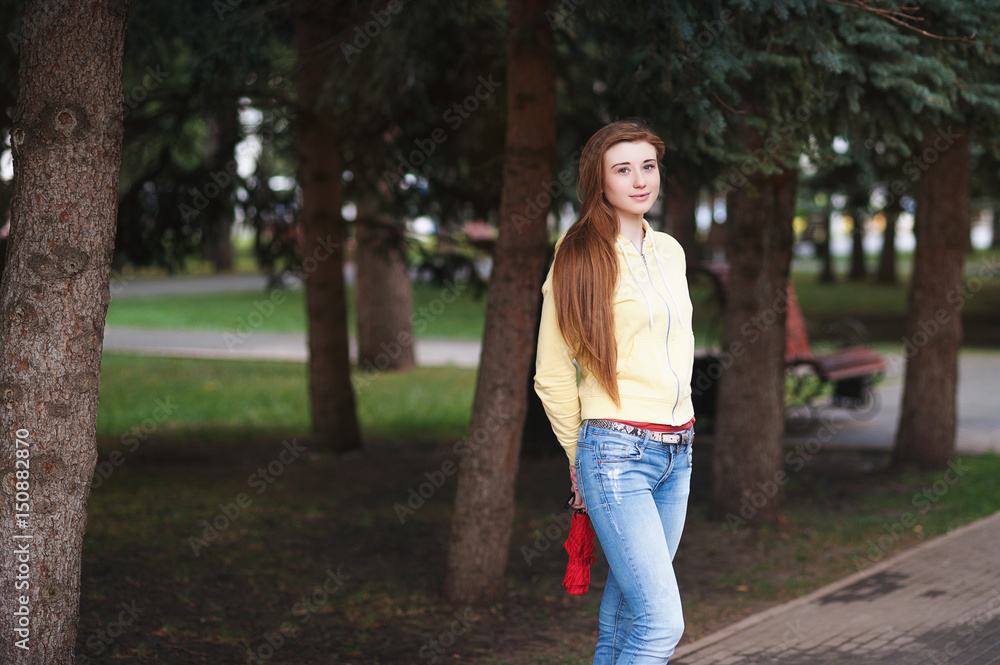 A pretty girl with long red hair, walks through the park and smiles Portrait in the open air A pretty girl with long red hair, walks through the park and smiles Portrait in the open air