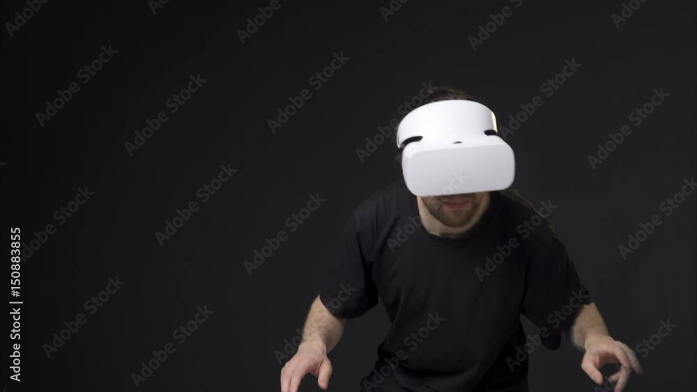 Young man in vr headset moving in virtual reality, black background Young man in vr headset moving in virtual reality, black background