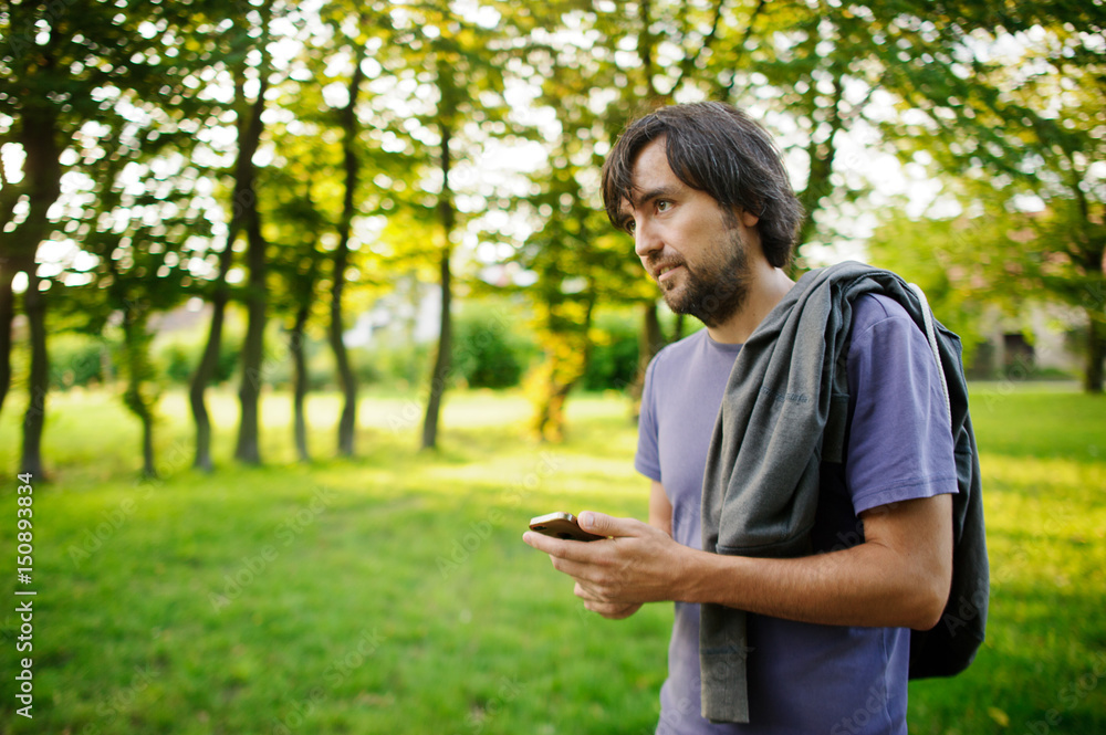 Young bearded guy looks thoughtfully at the screen of the smartphone. Young bearded guy looks thoughtfully at the screen of the smartphone.