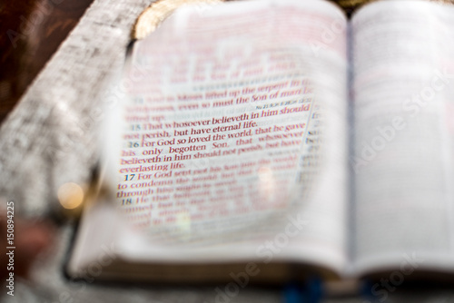 Reading the Bible with magnify glass John 3:16 