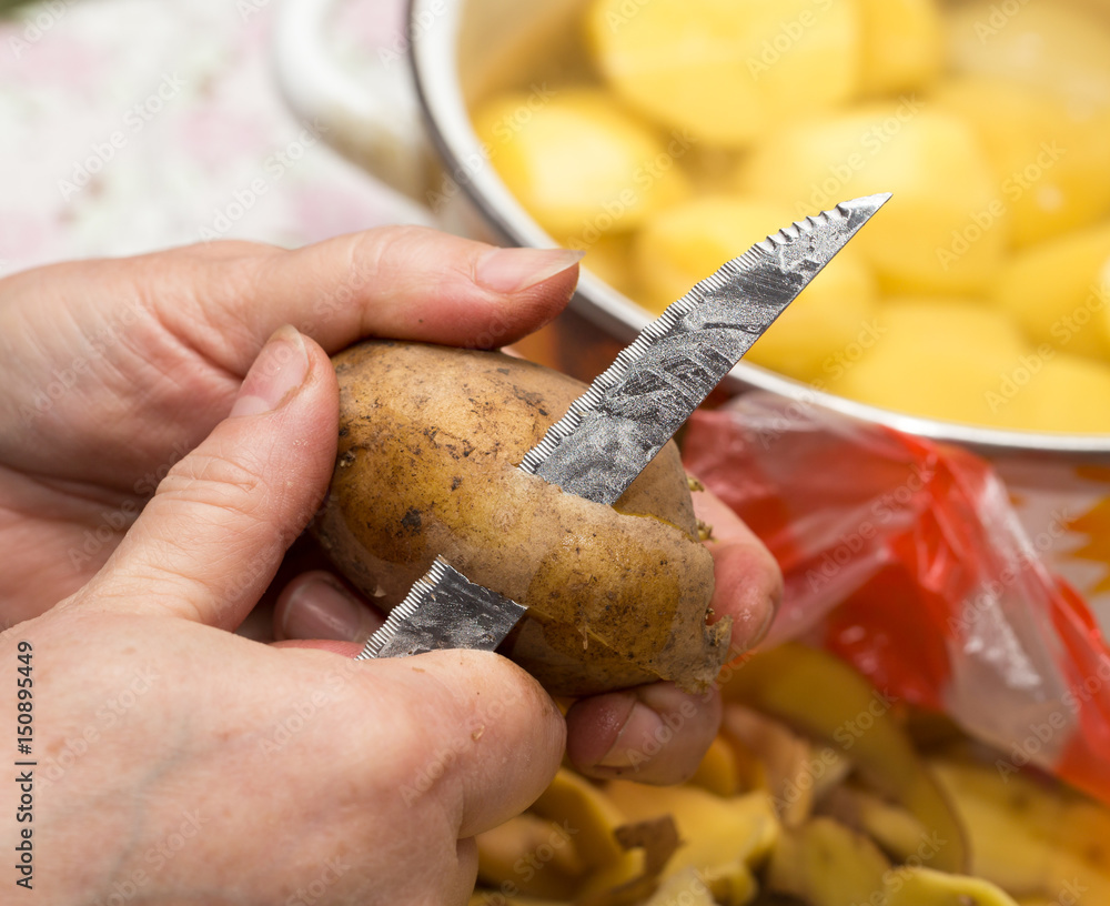 The cook cleans the potatoes with a knife The cook cleans the potatoes with a knife