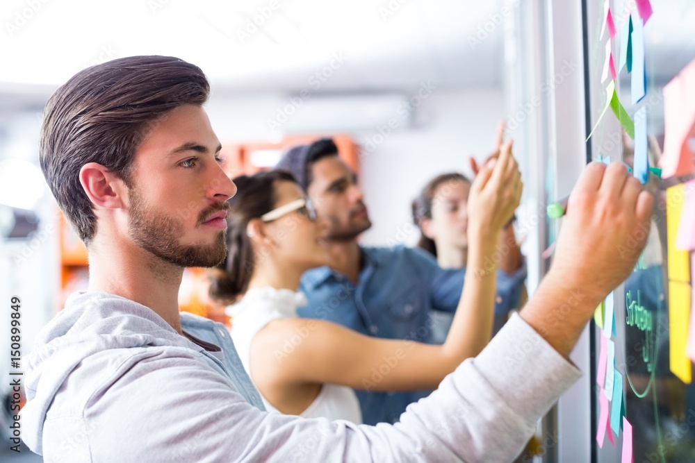 Male executive writing on sticky notes Male executive writing on sticky notes