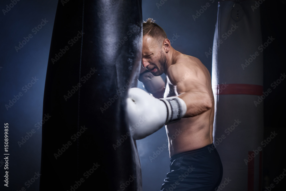 Male boxer using punch bag during training .