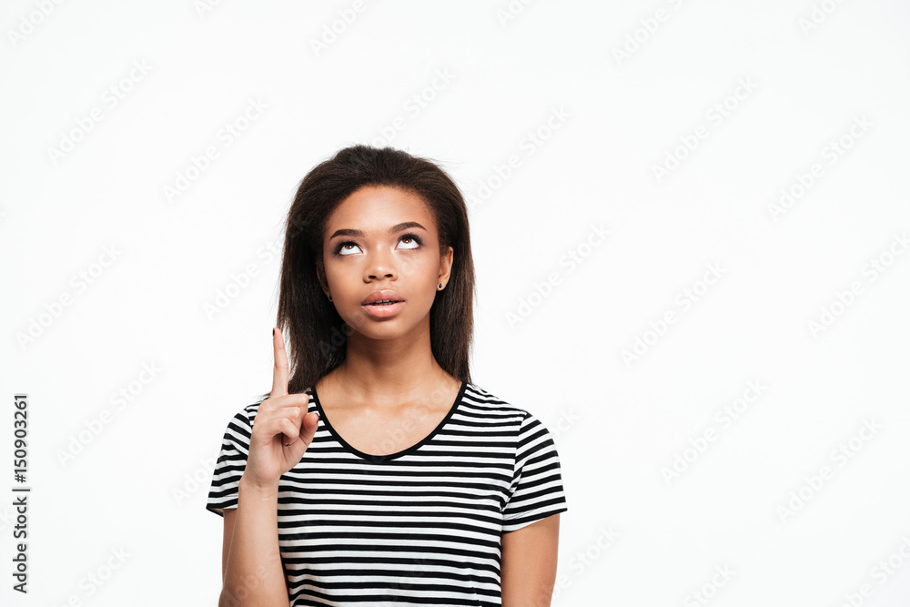 Thinking young african lady pointing and looking aside. Thinking young african lady pointing and looking aside.