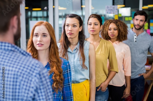 Serious colleagues standing in front of male executive © WavebreakMediaMicro