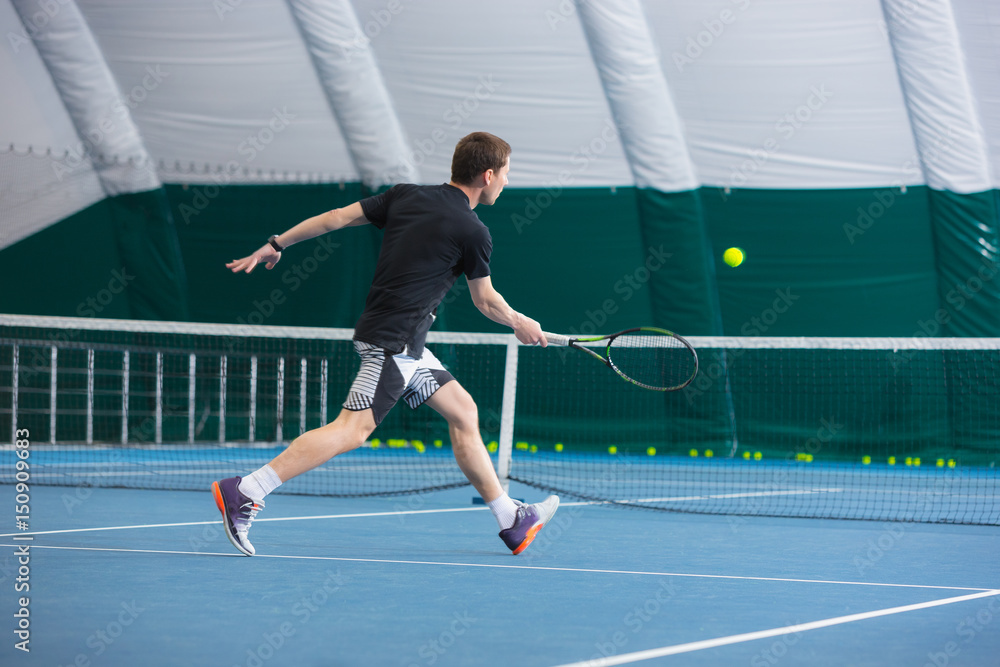 The young man in a closed tennis court with ball The young man in a closed tennis court with ball