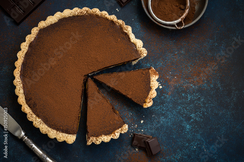 Fotografie chocolate and caramel tart on dark blue background