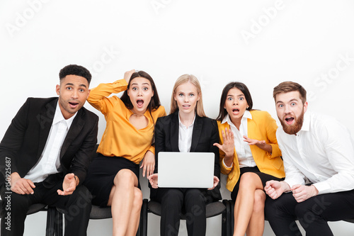Shocked colleagues sitting in office using laptop computer.