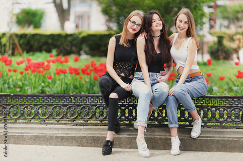 Three girls sit on the park background