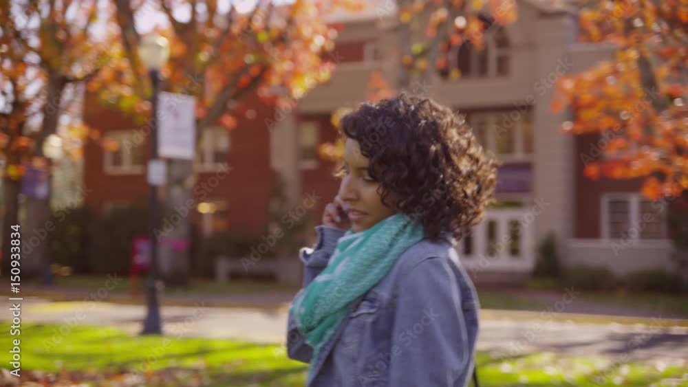 College student on campus in fall talking on cell phone College student on campus in fall talking on cell phone