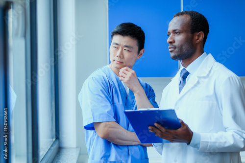 side view of multiracial group of doctors in medical uniforms with folder in clinic