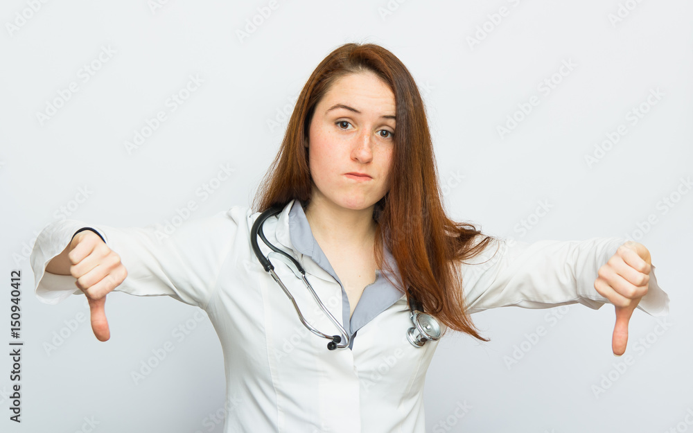 Displeased medical doctor woman showing thumbs down gesture on white background Displeased medical doctor woman showing thumbs down gesture on white background
