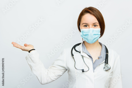 Beautiful successful female doctor with medical mask holding something on her hand