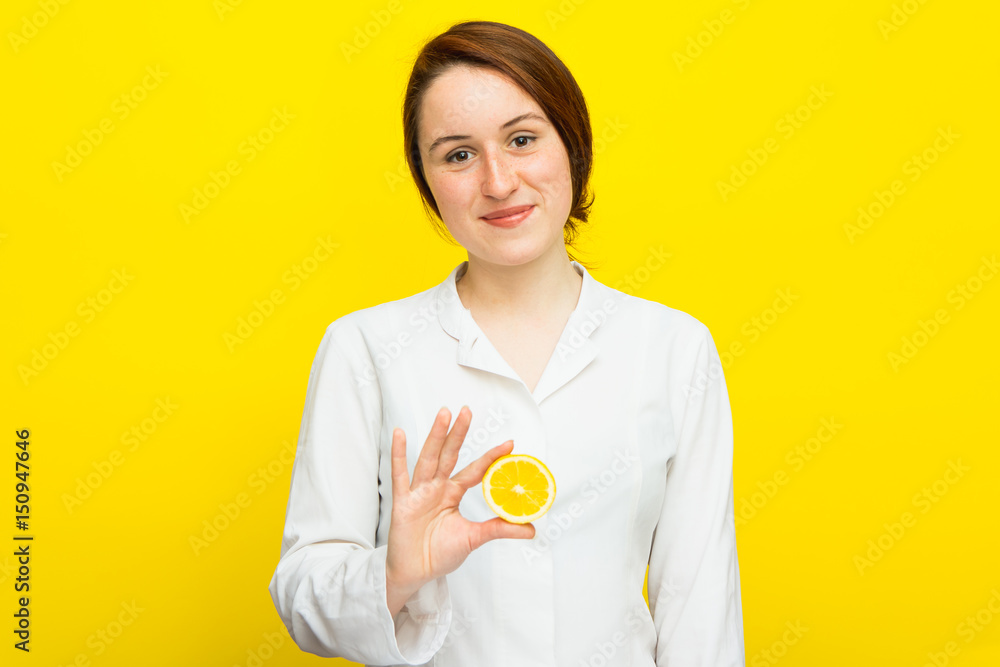 Young female nutritionist with half citrus on yellow background Young female nutritionist with half citrus on yellow background