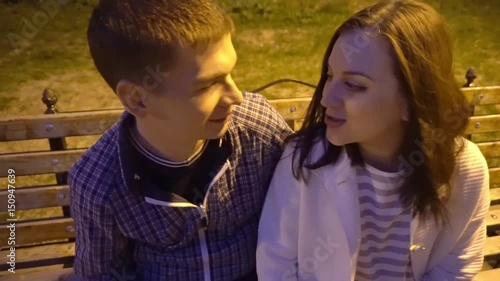 4k attractive young Couple in love at park bench hug, cuddle, embrace.Happy,in love,male and female couple in their 20's and 30's laugh hug and cuddle tracking shot. photo