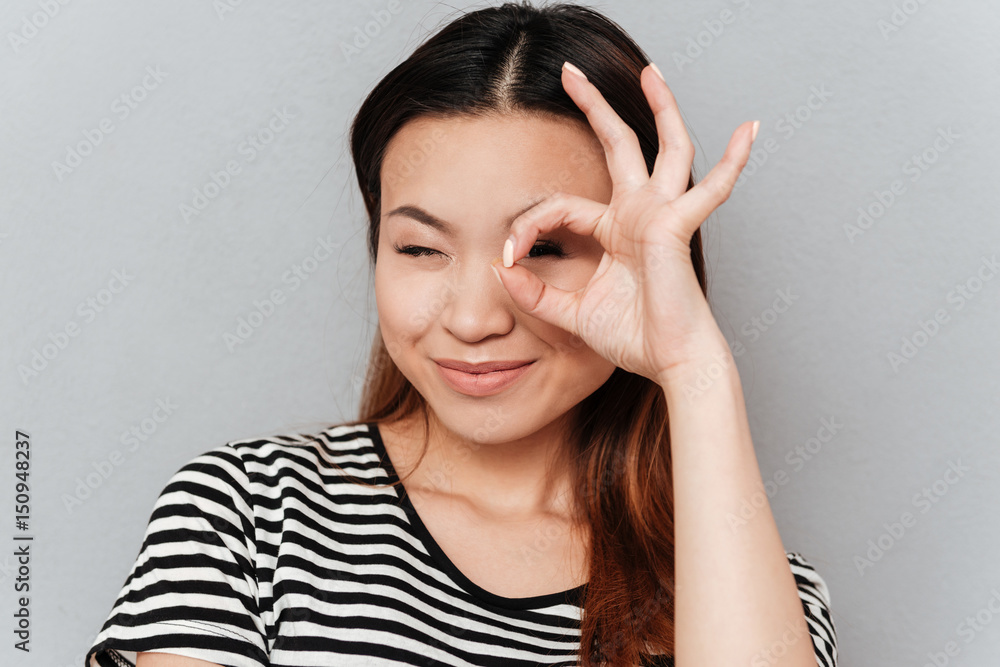 Woman looking camera showing ok gesture near face Woman looking camera showing ok gesture near face