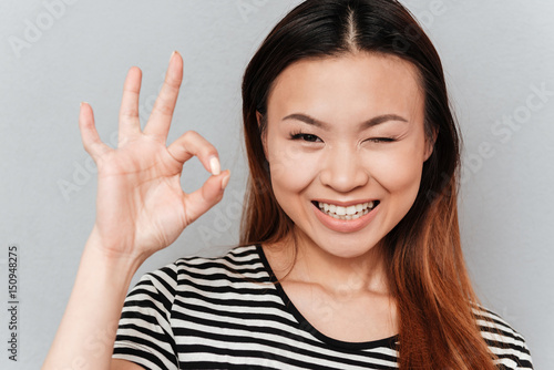 Wallpaper Mural Winking young woman showing ok gesture Torontodigital.ca