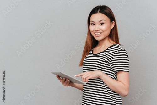 Smiling young woman using tablet computer.