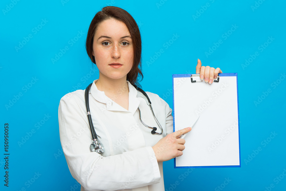 Young beautiful female doctor showing blank area for sign or copyspace, blue background Young beautiful female doctor showing blank area for sign or copyspace, blue background