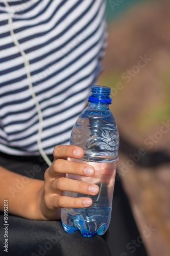 A bottle of water close-up. The girl drinks water during fitness outdoors