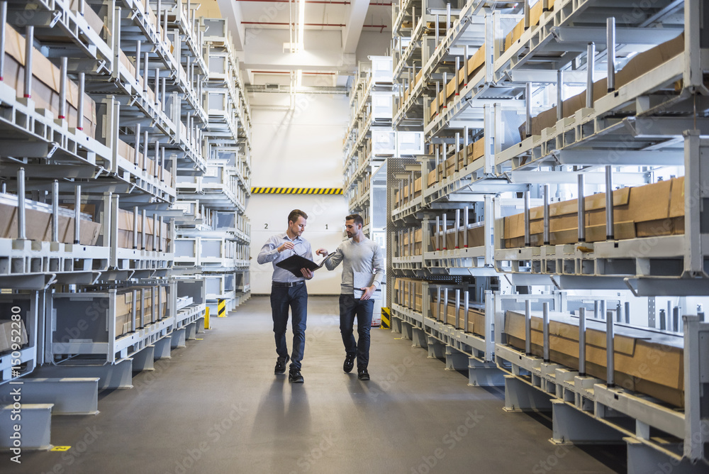 Two men walking in factory warehouse Two men walking in factory warehouse