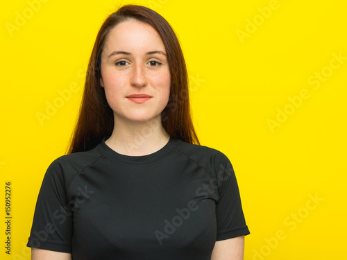 Happy young woman in black T-shirt on yellow background