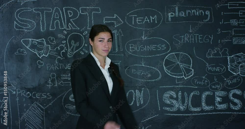 Beautiful business girl, marketing teacher, draws a graph of success on a black board, on a black background. Concept: career growth, growth chart, successful girl, marketing, ideas, finances. Beautiful business girl, marketing teacher, draws a graph of success on a black board, on a black background. Concept: career growth, growth chart, successful girl, marketing, ideas, finances.
