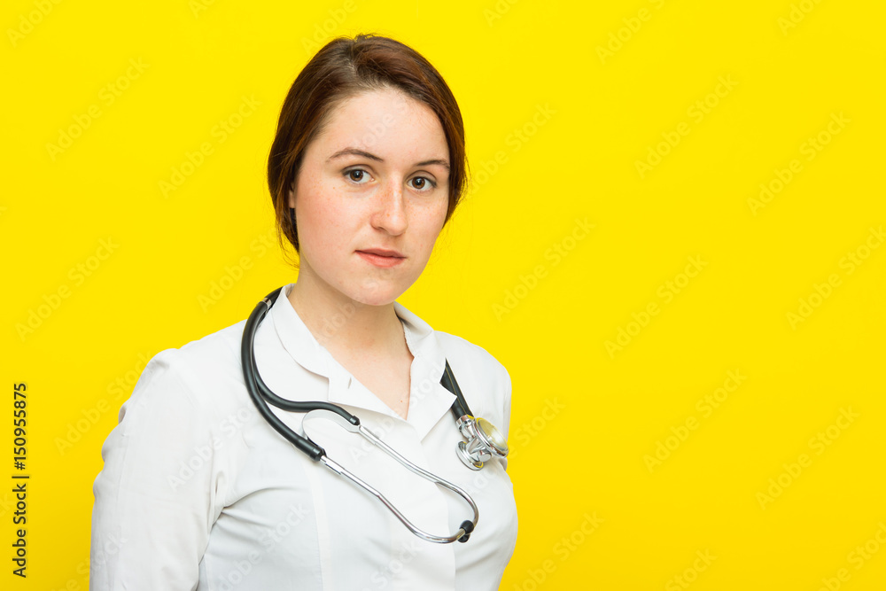 Young female doctor with a stethoscope on yellow background Young female doctor with a stethoscope on yellow background