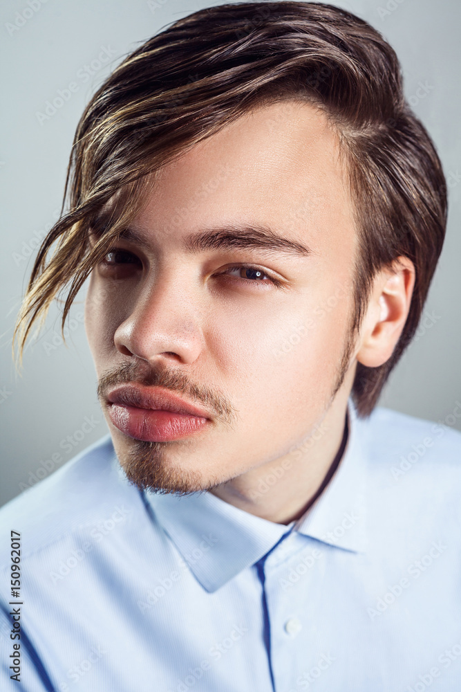 Portrait of young man with long fringe hairstyle on his eyes. studio shot. looking at camera. Portrait of young man with long fringe hairstyle on his eyes. studio shot. looking at camera.