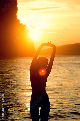 Female body silhouette against bright sea sunset and sunny islands on horizon line