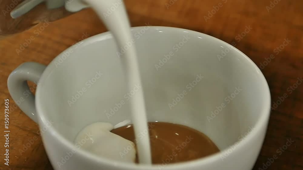 Pouring stream milk into a cup of coffee Pouring stream milk into a cup of coffee