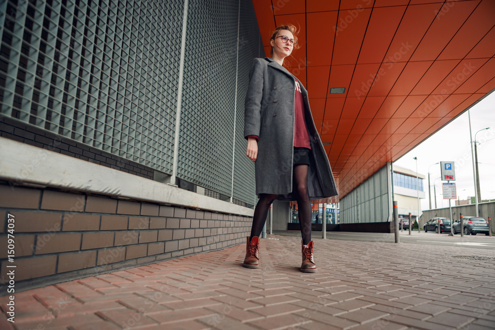 Beautiful and young girl in a coat and scarf and sunglasses walking around the city in the summer. Beautiful and young girl in a coat and scarf and sunglasses walking around the city in the summer.
