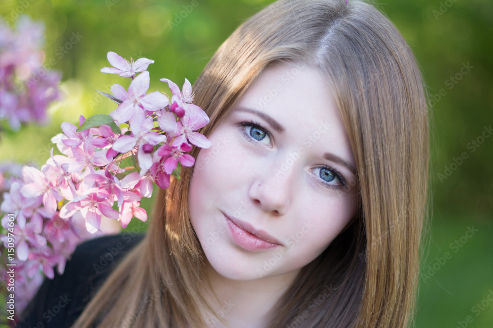 Portrait of a girl with a flowering branch, looking with enamored eyes Portrait of a girl with a flowering branch, looking with enamored eyes