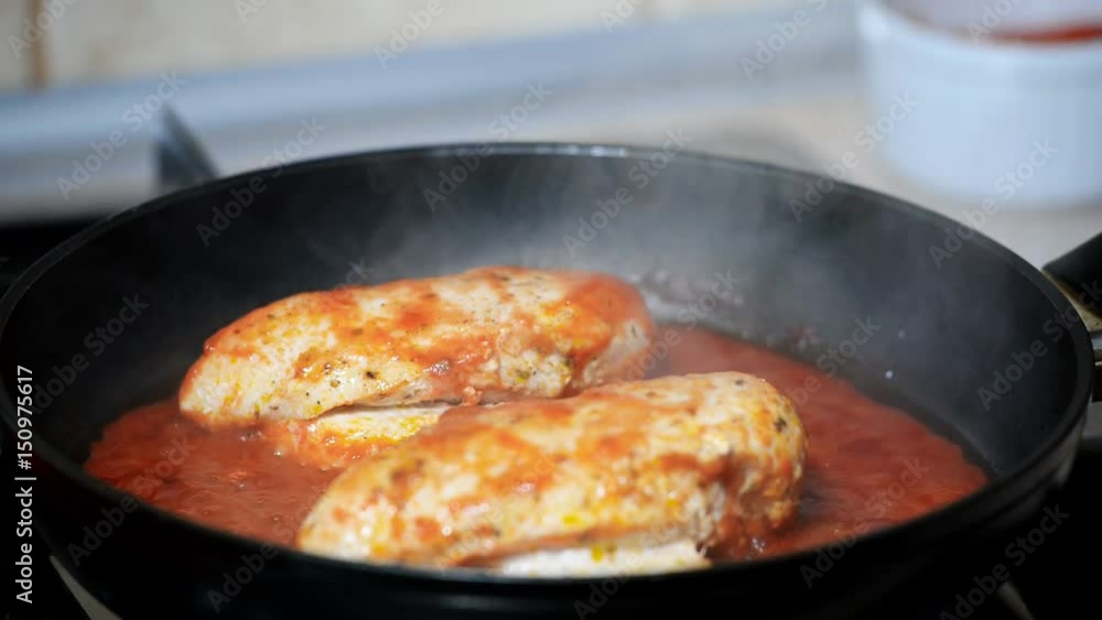 A woman cook chicken in tomato sauce. Hand open pan cover. A woman cook chicken in tomato sauce. Hand open pan cover.