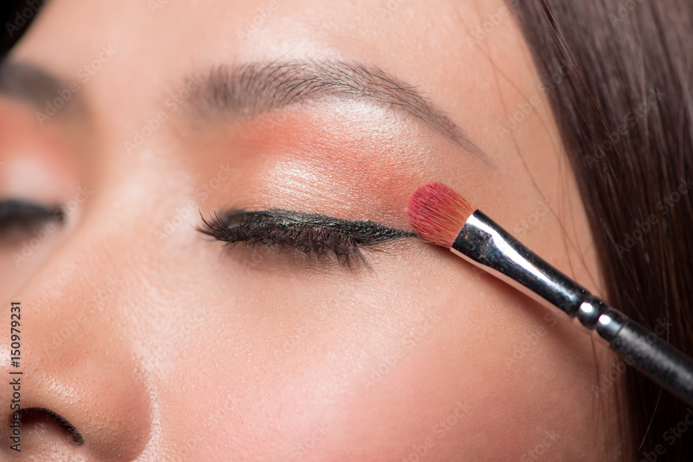 Beautiful asian woman face with perfect makeup applying blusher.