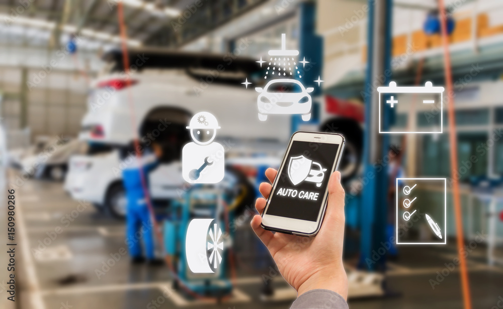 auto care application on smartphone with Blurred picture of car garage with cars being under maintenance and technicians for background auto care application on smartphone with Blurred picture of car garage with cars being under maintenance and technicians for background