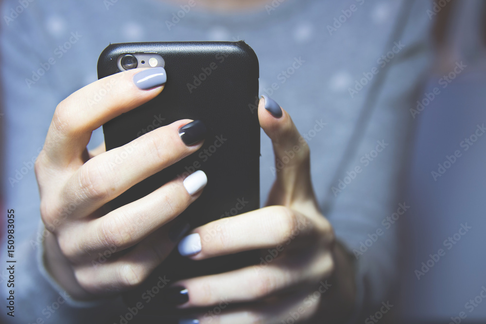 Female hands with black, grey and white polished nails hold mobile phone Female hands with black, grey and white polished nails hold mobile phone