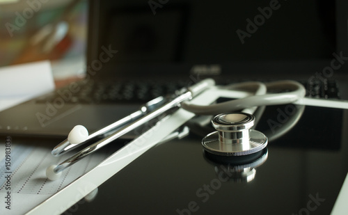 Stethoscope on screen tablet, laptop computer at medicine doctor work, selective focus, classic tone