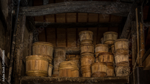 Rows of traditional wooden stake barrels with bamboo hoops wait on the street behind a soy souce brewing factory warehouse in Japan.